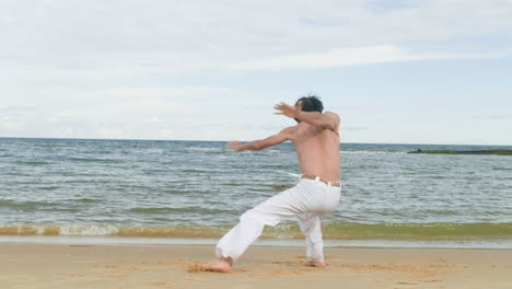 un tipo bailando capoeira en la playa.