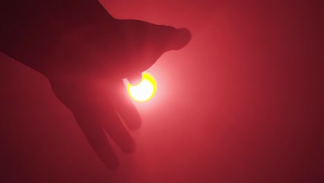 video vertical: la mano se extiende hacia la luz, el fondo rojo, el concepto en apuros