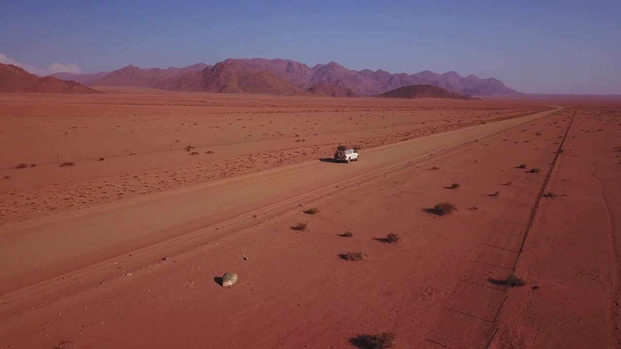 Carro visto por trás dirigindo em estrada deserta vazia na Namíbia, Aéreo