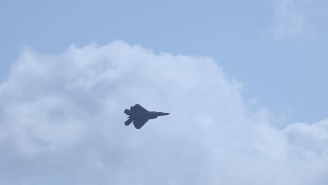 an f-22 raptor jet flies against a backdrop of clouds, showcasing its agility and power in a clear blue sky
