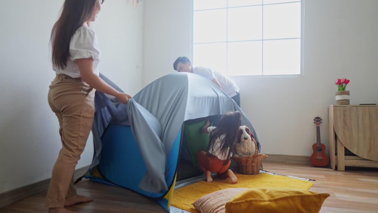 familia asiática emocionada preparando una tienda en casa con tela