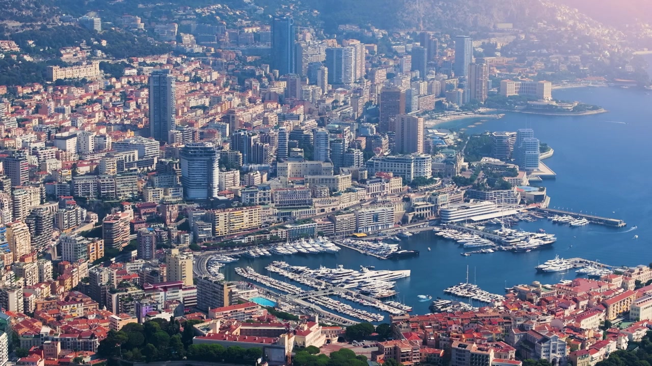Il porto di Monaco è pieno di yacht e barche, mentre lo skyline mostra edifici alti e viste costiere. Questa vista cattura la vivacità della città e le sue attività sul lungomare.