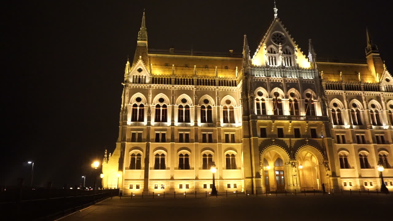 Side View Of The Beautiful Budapest Parliament In Kossuth Lajos Square, Hungary At Night - slow panning shot