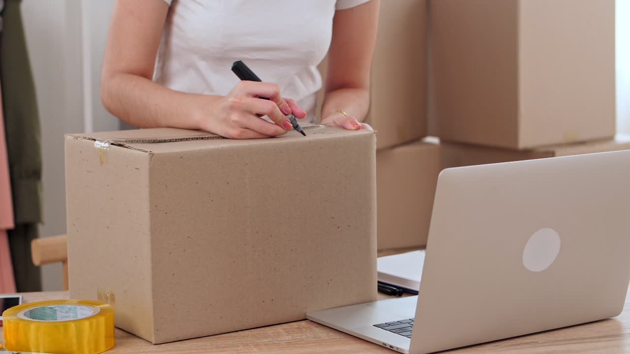 Young Asian Woman Entrepreneur Write On Cardboard Box For Shipping Shopping Online