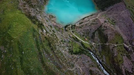 aerial, tilt, drone shot overlooking crystal clear, blue water of lake humantay, in the andes mountains, on a cloudy day, in peru, south america