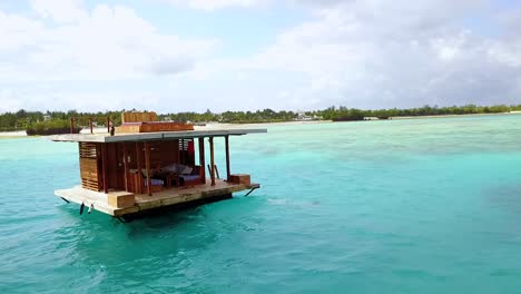 Aerial-Of-A-Woman-Jumping-Off-A-Floating-Gazebo-Into-The-Ocean-In-Tanzania