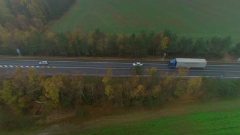 trucks and cars passing through an autumn landscape covered in fog