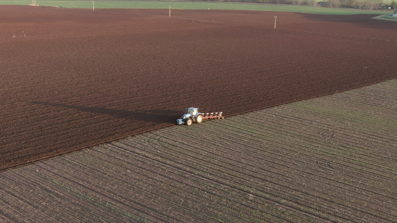 Vista aerea di un trattore agricolo che ara un campo ad Aberdeenshire in una giornata di sole, Scozia