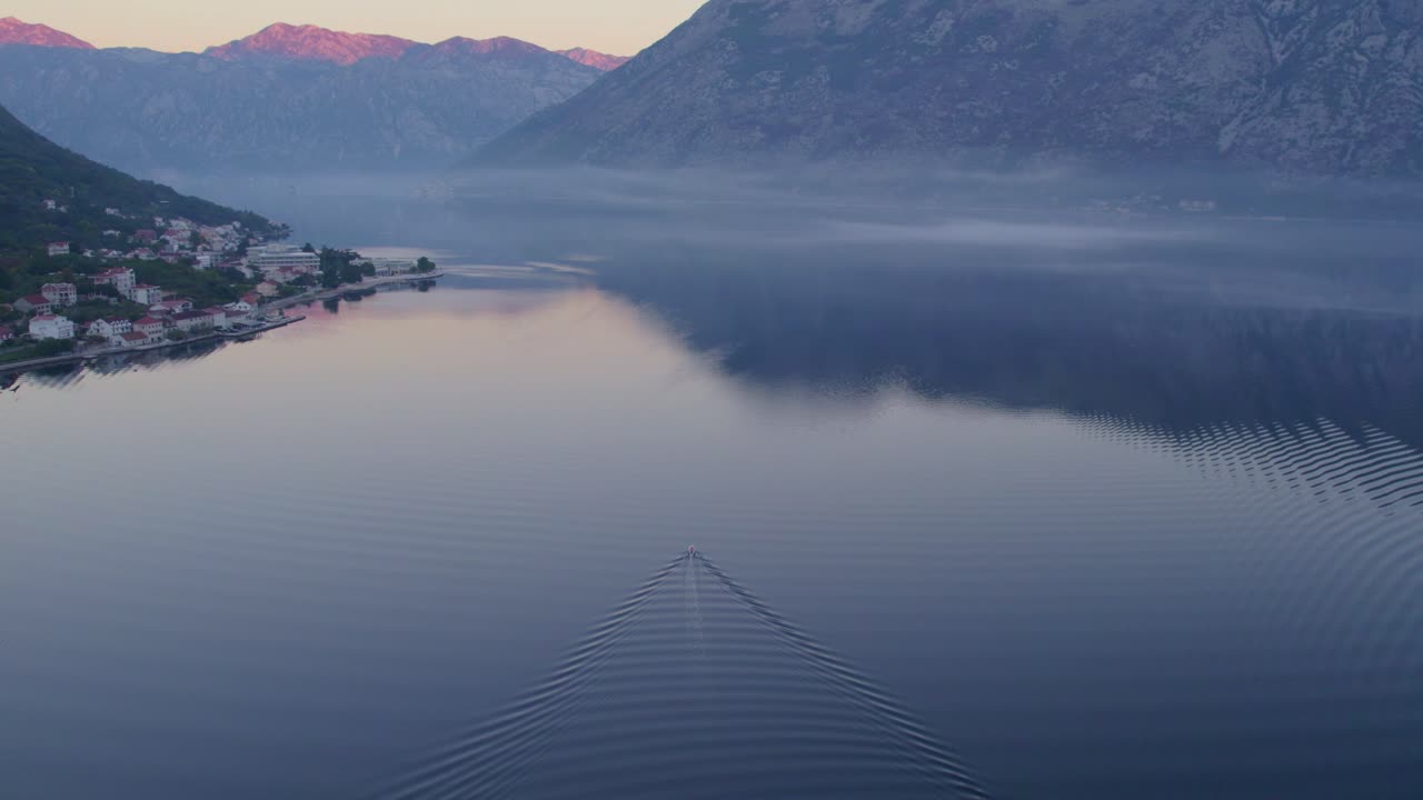 Boat cruises during golden hour at Kotor bay, aerial