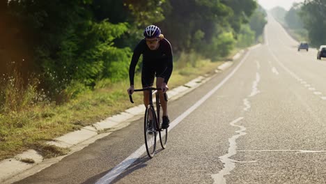 cyclist in helmet rides bicycle along the track, gaining speed