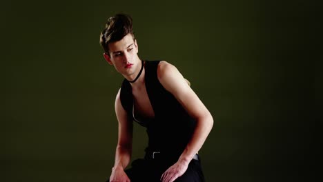 androgynous man in waistcoat posing against green background