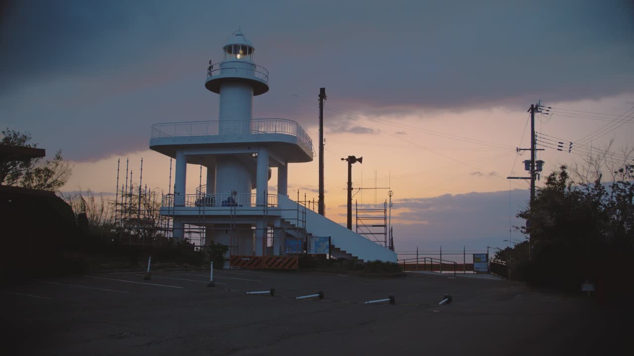 일본 사이카자키에 있는 그림 같은 등대는 황금 시간의 해가 지는 하늘을 배경으로 서서 조용한 저녁 장면을 만니다.