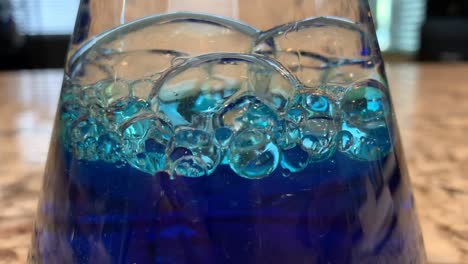 an ocean in a bottle science experiment for kids mixing baby oil, water, and blue food coloring