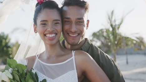 portrait of happy diverse bride and groom smiling at sunny beach wedding, in slow motion