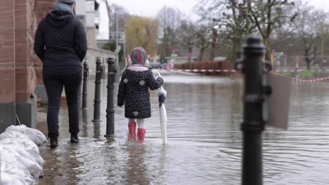 mother and daughter walk on the flooded sidewalk in eltville town in germany