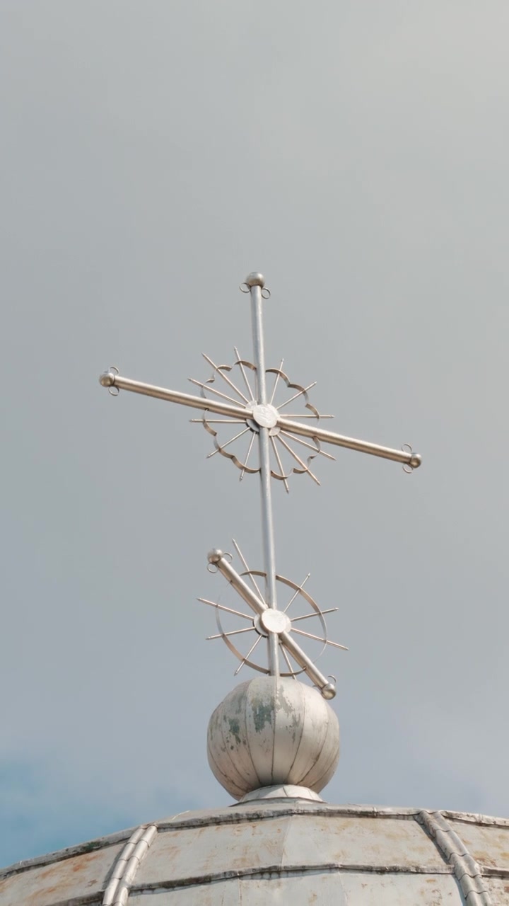Metal cross on top of a church against a clear sky