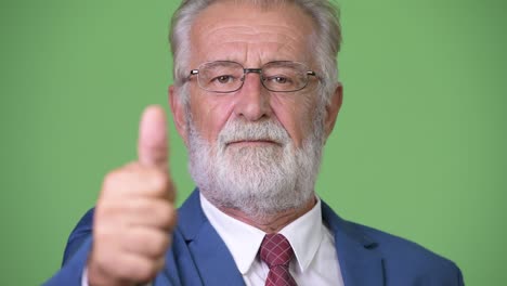 hombre de negocios barbudo y guapo contra un fondo verde.