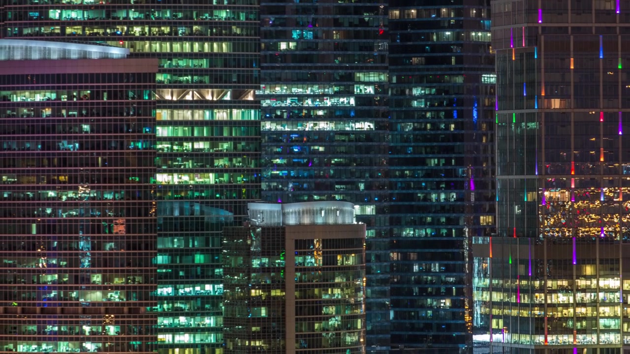 Modern office building with glowing windows at night timelapse. Moscow city. Close up view from rooftop. Zoom out