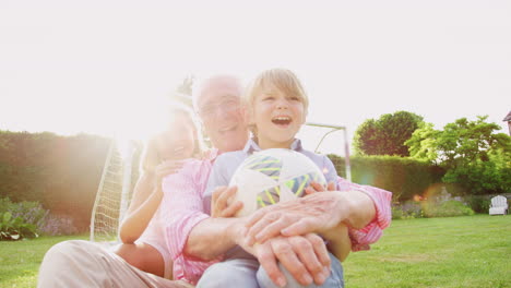 Grandad-and-grandkids-sitting-in-garden-with-football