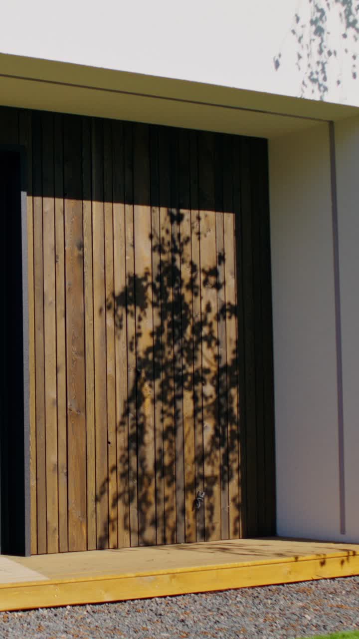 Modern House Exterior with Wooden Siding and Tree Shadow