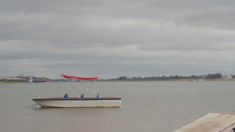 a tied boat in the river, cloudy day, windy day