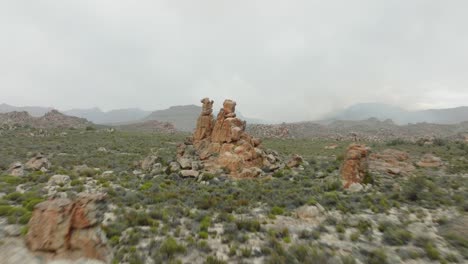 drone flies fast over rocks towards rock formation in desert landscape cederberg wilderness area in south africa - mountains can be seen in the background