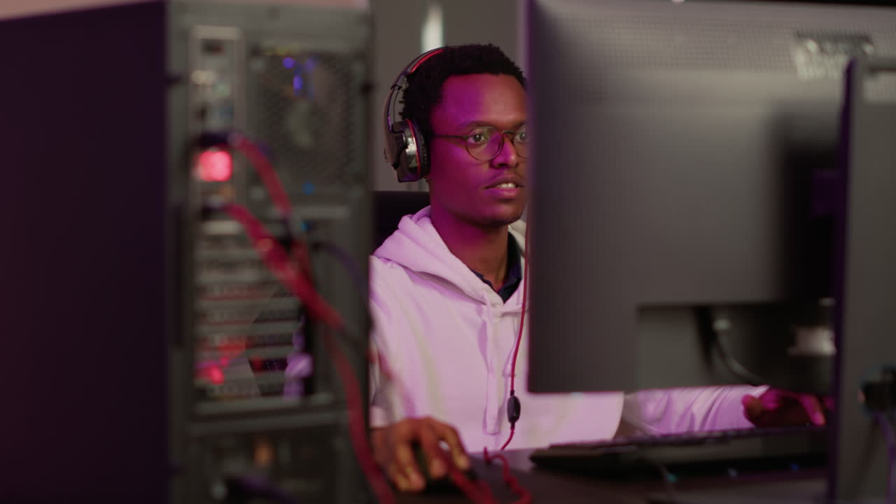 Selective focus on african american gamer using gaming pc professional setup while having fun playing online games