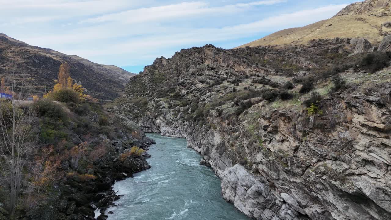 Aerial footage of Kawarau Gorge in Queenstown, New Zealand, showcasing autumn colors and a winding river under soft daylight
