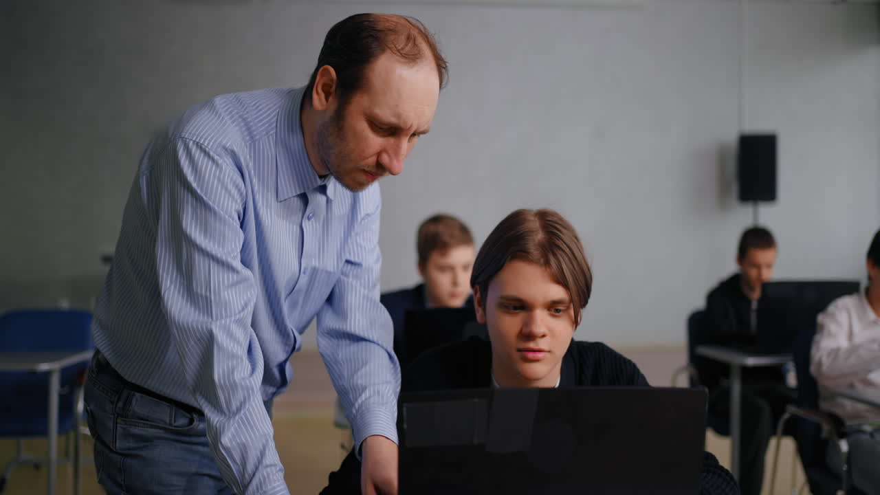 교실에서 노트북으로 학생을 돕는 교사