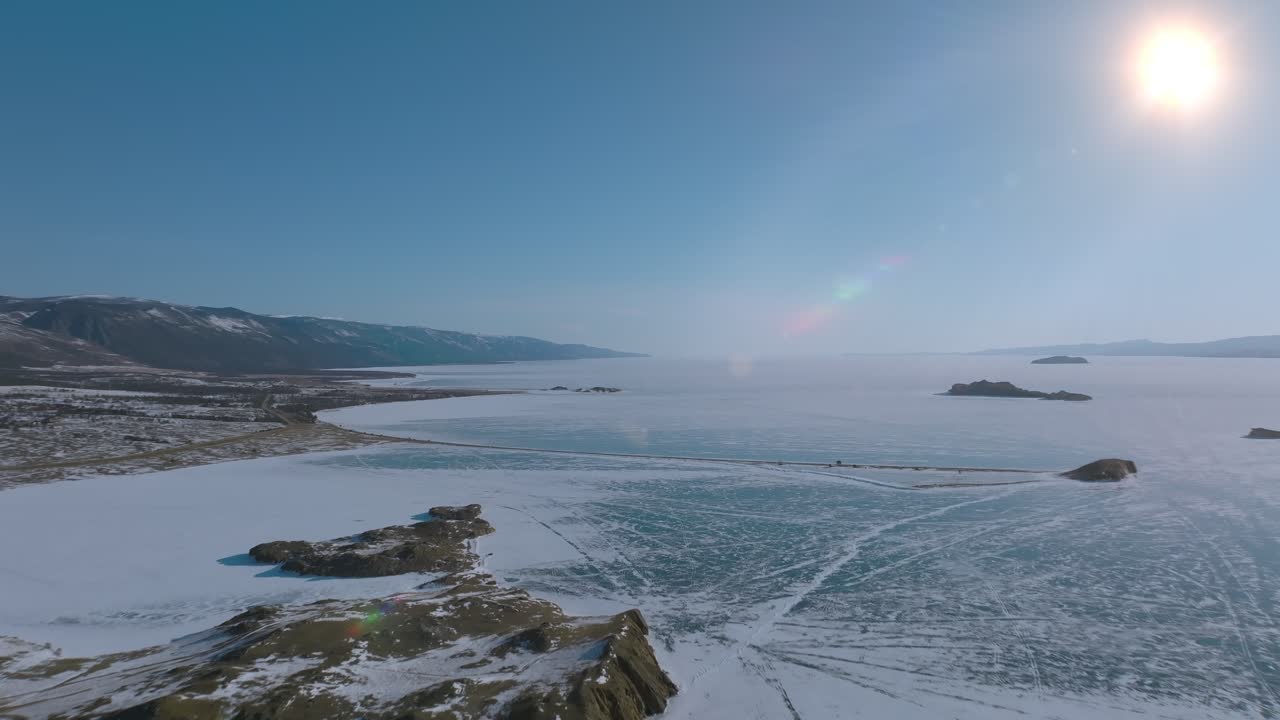 Droneoptagelser af Maloye More-strædet på den frosne Bajkalsø med snedækkede øer, klare ismønstre og klar sol over kystlinjen, Irkutsk Oblast, Rusland