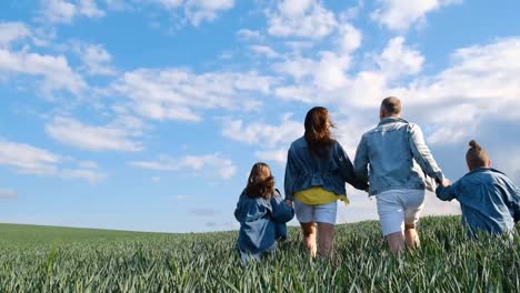 mom dad and two children run happily among the fields against the blue sky mom dad and two children run happily among the fields against the blue sky family weekend happiness to be together