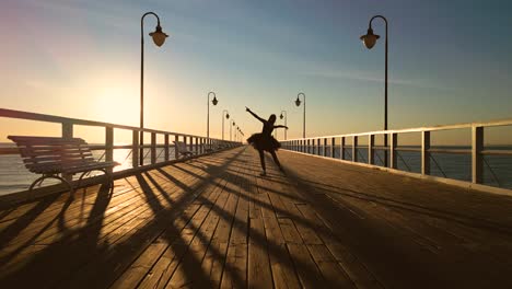 ballet dancer practicing in beach pier at sunrise