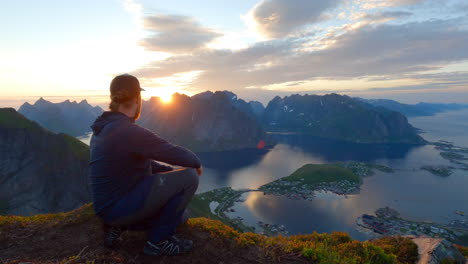 joven viajero levantando los brazos y disfrutando de la vista en la cima de la montaña, sol de medianoche, lofoten