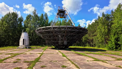 vista lateral del centro internacional de radioastronomía de ventspils con un bosque verde a su alrededor, cámara lenta y un cielo azul