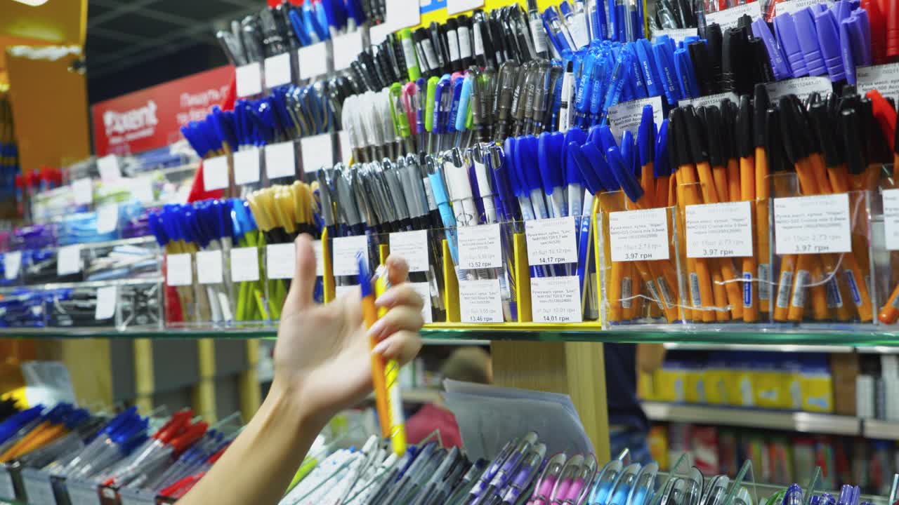 Vinnycja, Ukrajina – 20. srpna 2018: Nákup papírnického zboží v obchodě. Ženská ruka vybírá pera.