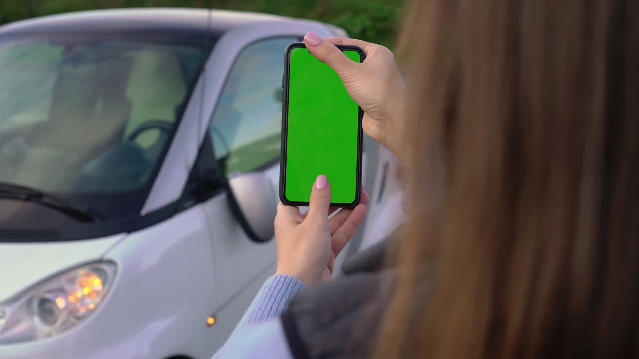 chica con pantalla verde móvil toma fotos en el estacionamiento. accidente automovilístico espejo roto