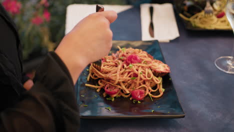 woman using a fork to eat spaghetti with lobster and tomato sauce