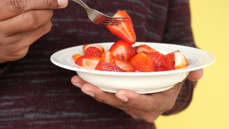 persona comiendo un plato de fresas con un tenedor