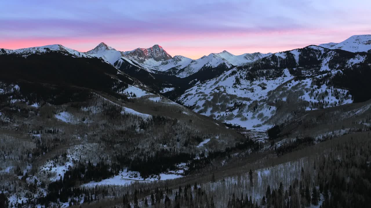 Montagne Rocciose Colorado, 14er Capitol Peak, sentiero di valle, drone aereo, inverno, tramonto viola, paesaggio naturale panoramico. Valle di Aspen Snowmass, Catena montuosa Elk, Longs Peak, Area selvaggia Maroon Bells. Movimento: panoramica in avanti e verso l'alto.