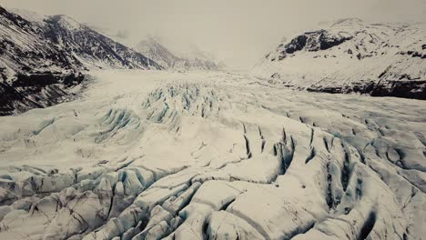 Glacier-tongue-in-Iceland-filmed-by-drone-with-different-cinematic-movements,-showing-a-cloudy,-dramatic-concept-in-wintery-conditions