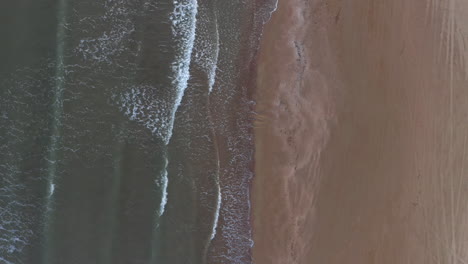 aerial: top down orbit shot of a sand beach near katakolo with seaside houses during dusk