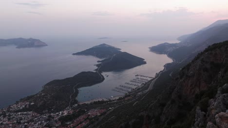 vista panorámica de la costa de kas con la bandera turca de pie con orgullo en la cima de una colina en el centro por encima del océano y la ciudad, aérea