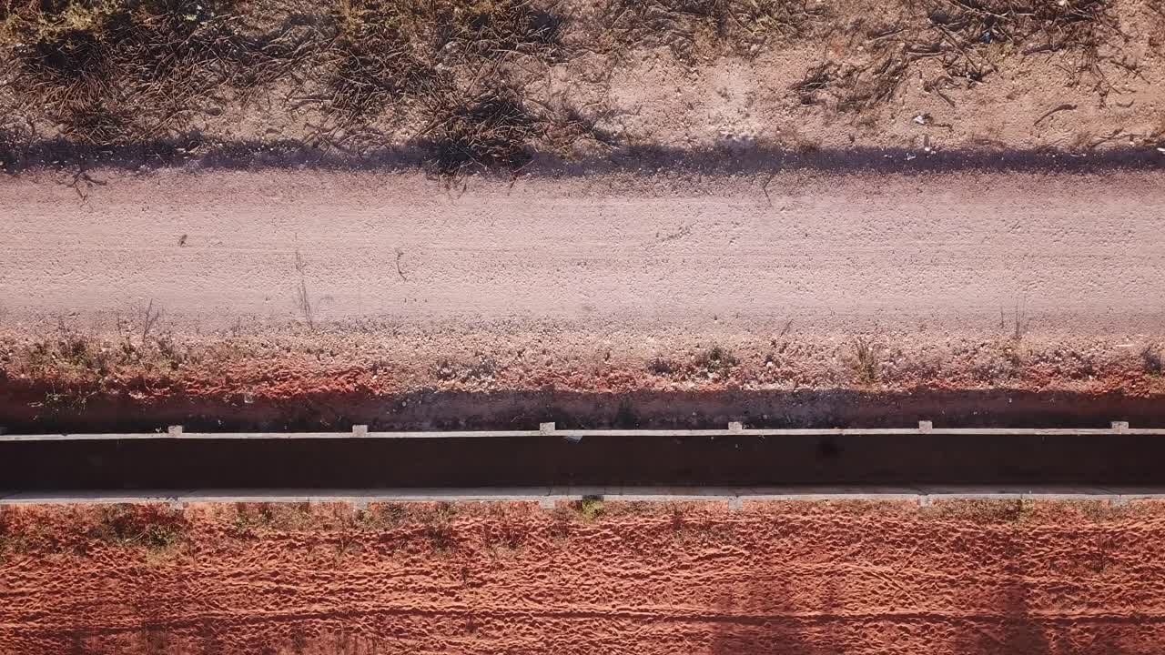 closeup top view of a motorbike driving trough a deserted red sand road casting a shadow