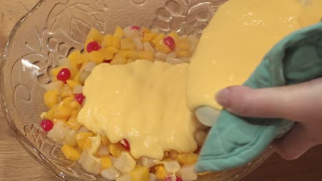 pouring custard over the fruit in an english trifle