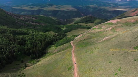 telluride airport aerial drone backwards motion last dollar road car colorado rocky ski resort san juans range mountains town summer dirt four wheel drive camping vista landscape sheep grazing land