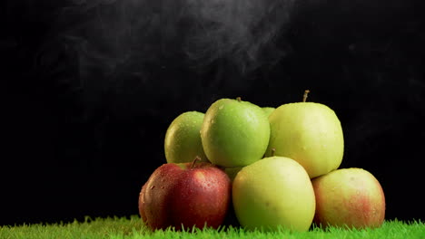 montón de manzanas de diferentes colores sobre fondo negro con vapor de humo encima