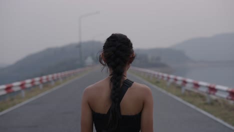 Woman Walking on a Road with Mountains in the Background