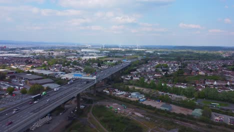 Static-drone-shot-over-River-Avon-facing-north-with-busy-M5-motorway-full-of-traffic-below,-and-wind-turbines-in-the-distance