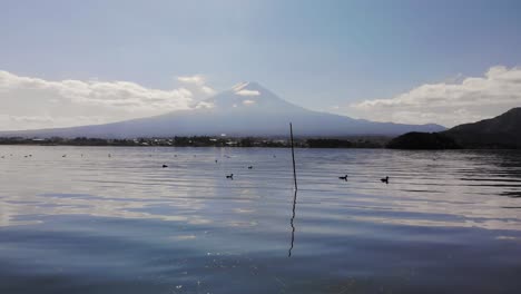 vuelo de drones de ángulo bajo cerca del agua hacia el monte fuji en un día brillante y soleado