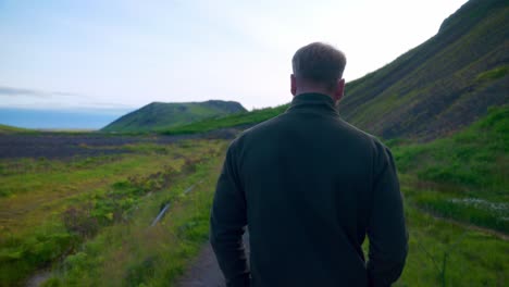 Guy-Walking-On-The-Trail-With-Mountainscape-Near-Seljavallalaug-In-Southern-Iceland